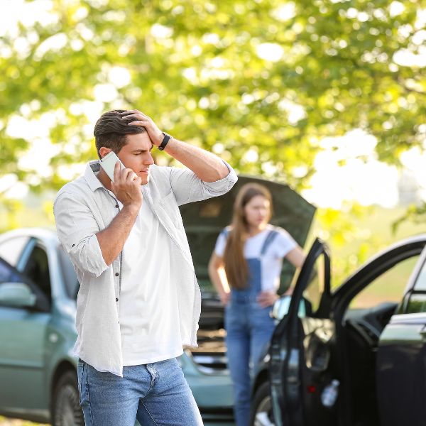 Two cars involved in a car accident and a man calling someone on his phone